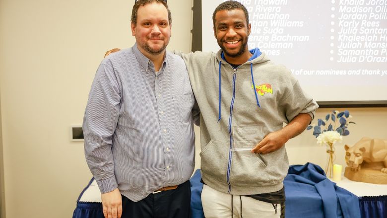 student and staff member with award