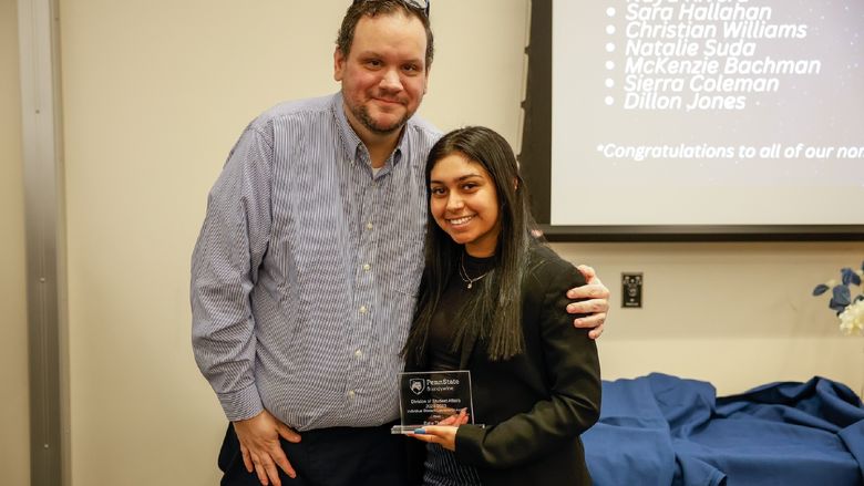 student and staff member with award