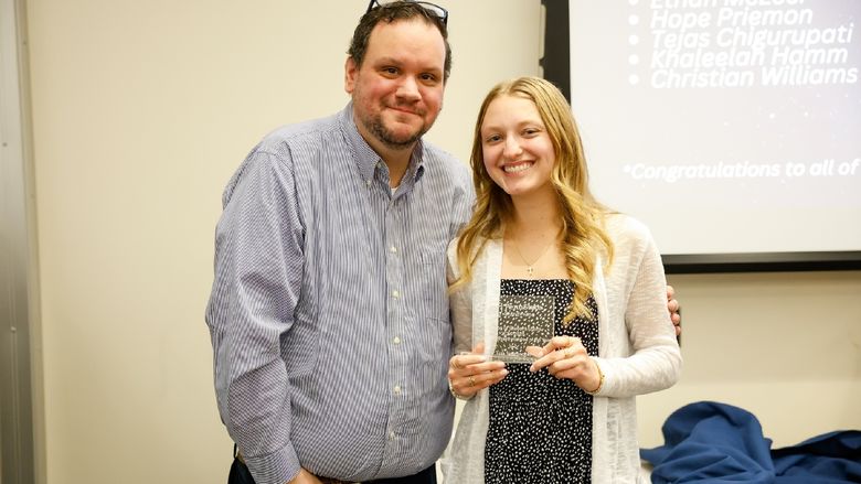 student and staff member with award