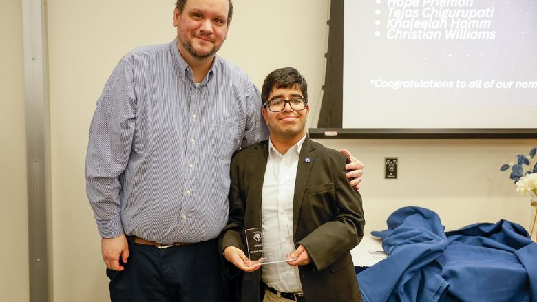 student and staff member with award