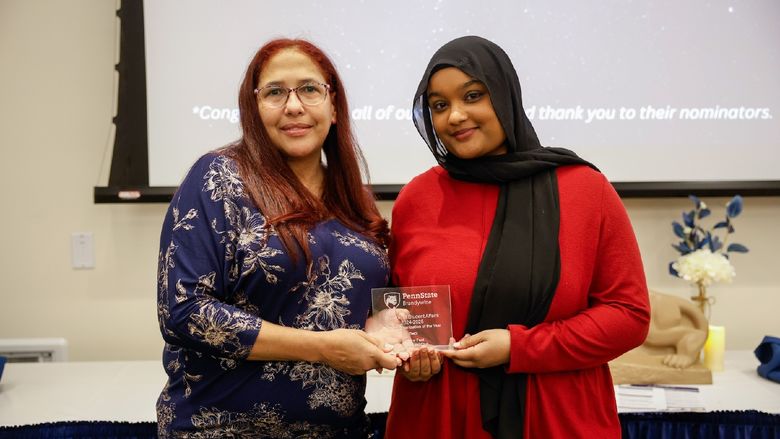 student and staff member with award