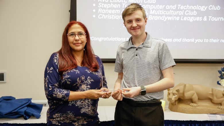 student and staff member with award