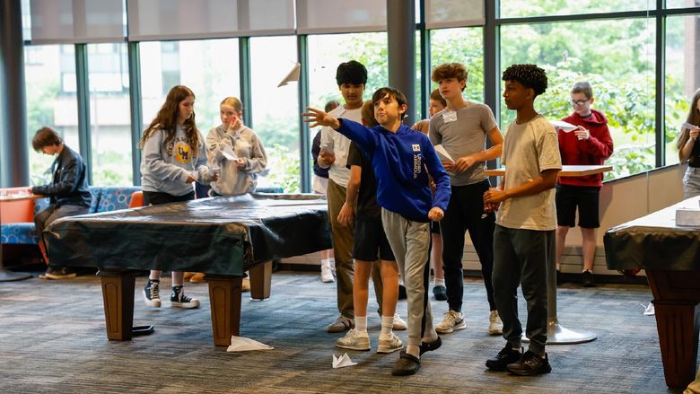 students flying paper airplanes