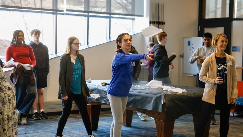 student flying paper airplane