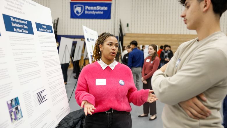 student presenting work on poster board