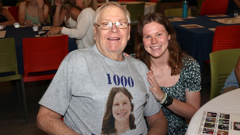 a woman and a man sitting next to each other, man wearing shirt that says 1000 points club