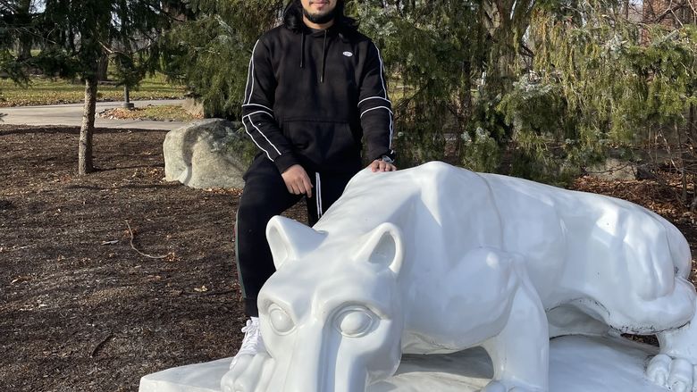 Student stands next to the lion shrine on the Penn State Brandywine campus.