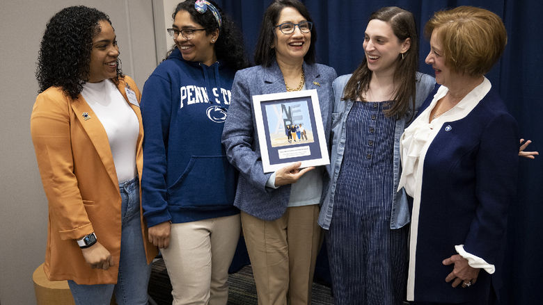 A group of five woman standing with one holding an artwork.