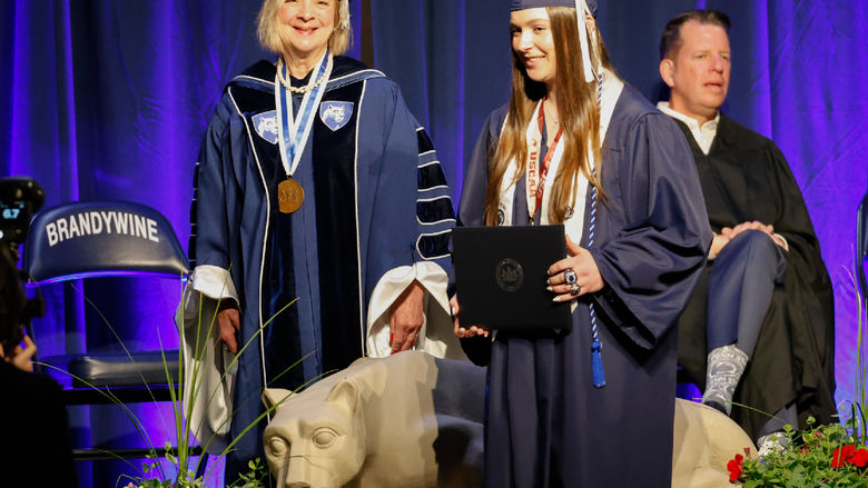 A female student receives her diploma at Brandywine's commencement ceremony.