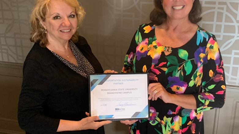 Two women hold up certificate at ceremony