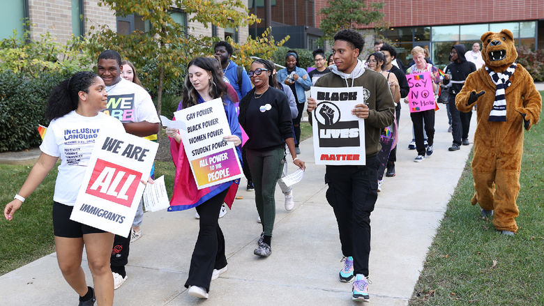 Students walk on campus carrying signs that support diversity, equity and inclusion.