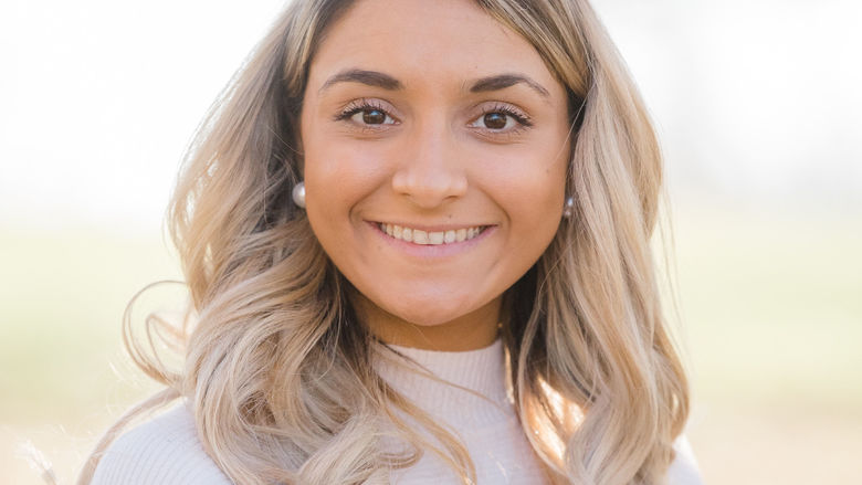 Woman with blonde hair wearing a white shirt, smiling
