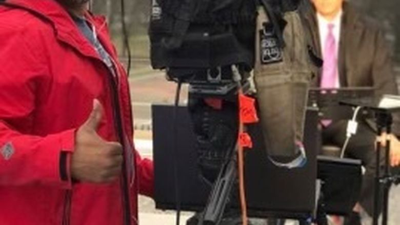 Man with thumb up behind a camera