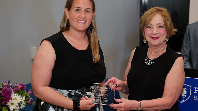 A woman receives an award from another woman.