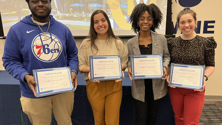 Four students hold certificates they received an an awards ceremony.