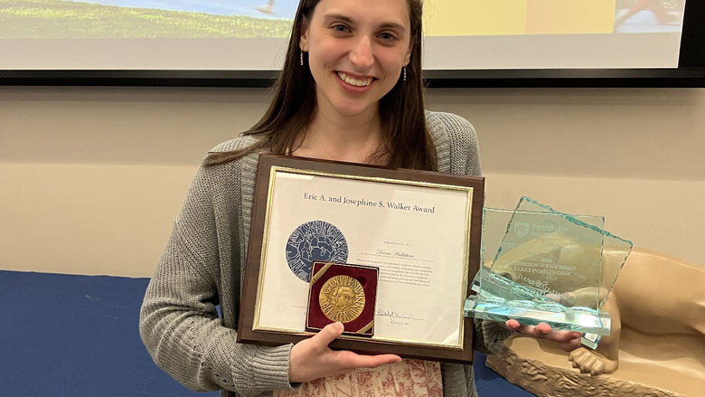 A female student holds an award certificate.