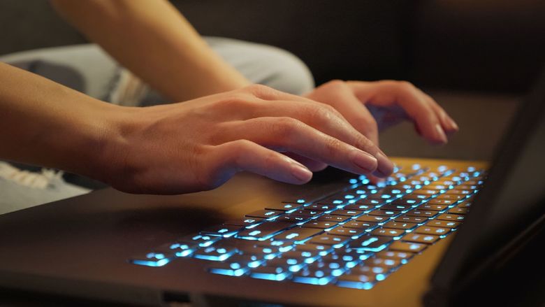 fingers hover over lighted laptop keyboard