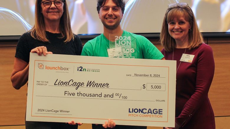 Eli Moraru, co-founder of the Community Grocer, poses with a giant check with prize money for his winning pitch.