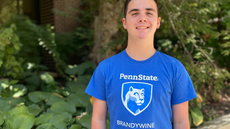 Cortez wearing a blue Brandywine shirt smiling in front of plants