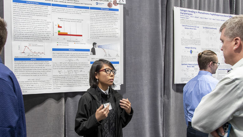 Girl presents research focusing on COVID-19 pandemic to a symposium judge