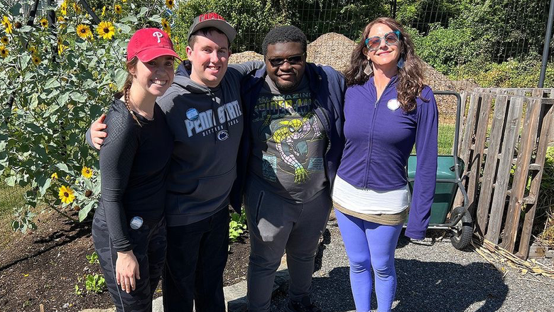 Students and garden manager standing in front of sun flowers
