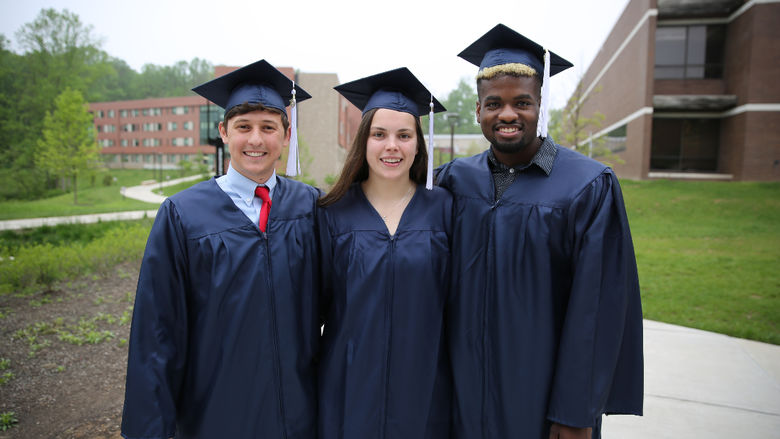 Three students smiling after Commencement ceremony.