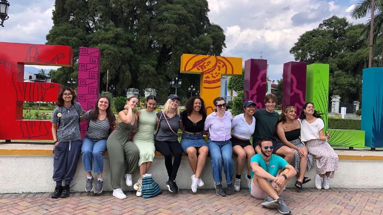 students sitting in front of sign that says "Santa Maria del Tule"