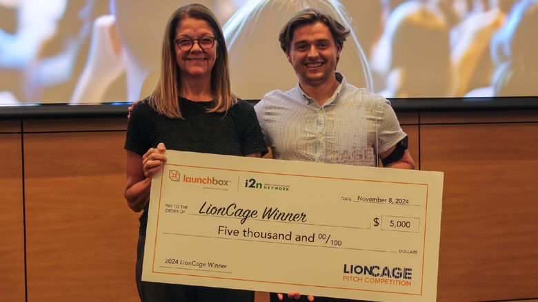 man and woman holding large checks