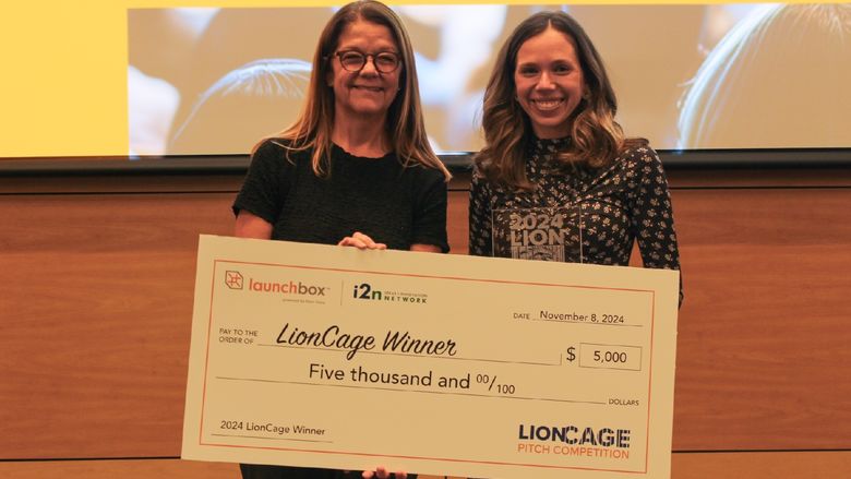 two women holding large checks