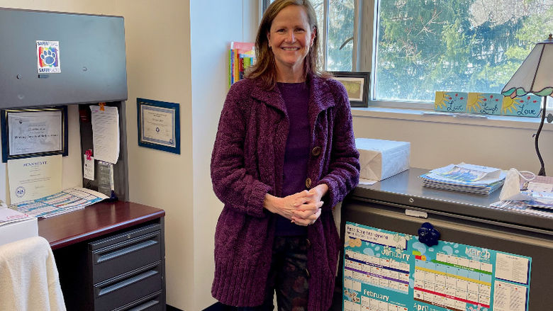 Christine Allen, Coordinator of Career Services stands in her office in front of a sign that reads "not all who wander are lost."