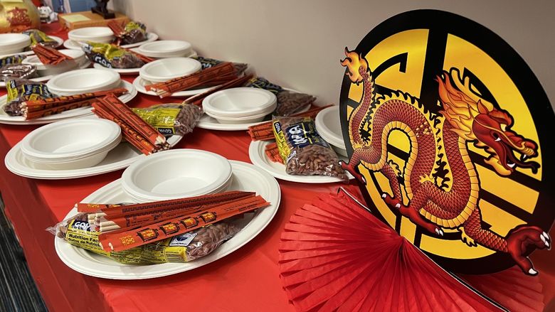 A table decorated for Lunar New Year including paper dragons, plates, chopsticks and a red tablecloth.