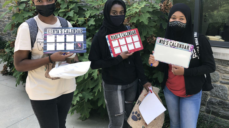 photo of three students holding white boards they created