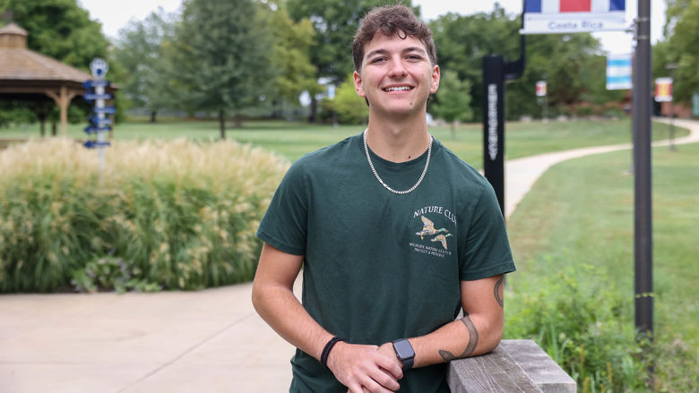 A male student stands on a sidewalk at Penn State Brandywine.