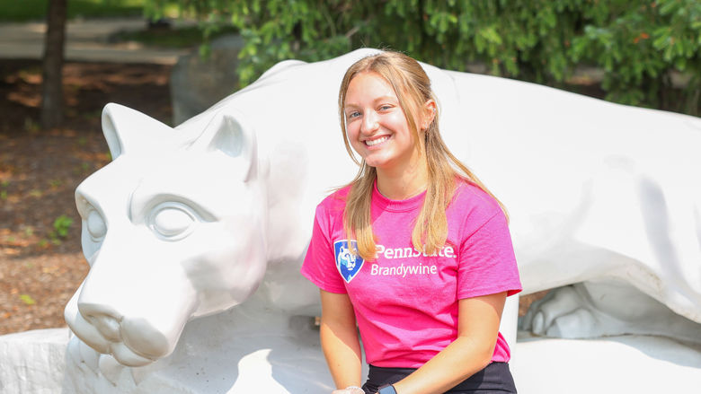 lady in pink shirt sitting next to lion shrine