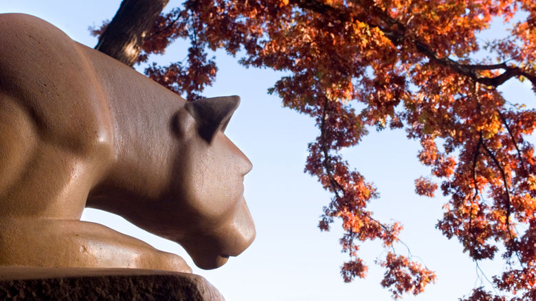 Nittany Lion Shrine with red fall leaves overhead.