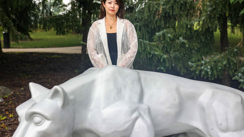 Luna Yang standing behind Nittany Lion shrine