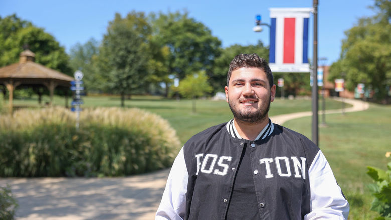A male student stands on a campus sidewalk at Penn State Brandywine.