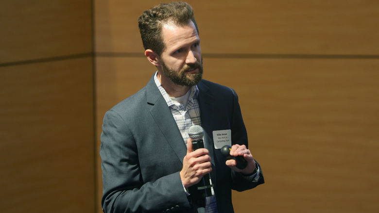 man speaking on stage with microphone