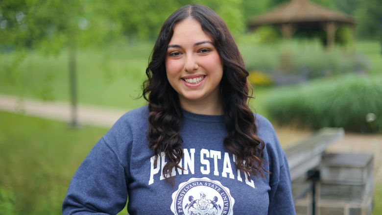 woman wearing blue Penn State sweatshirt leaning on a bridge