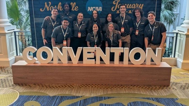 students posing for photo behind "Convention" sign