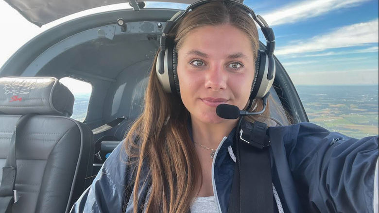 A female sits in the cockpit of a small plane.