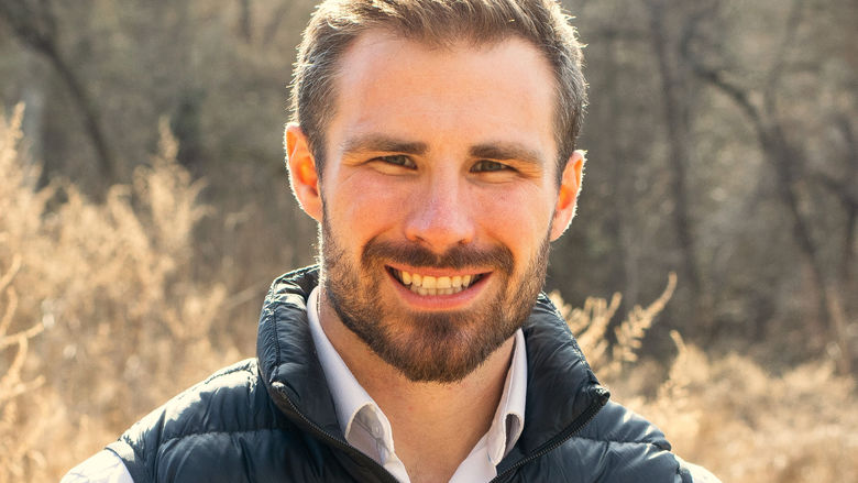 A head shot of a man standing outdoors.