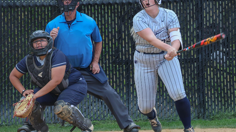 A female softball player looks ahead after hitting the ball.
