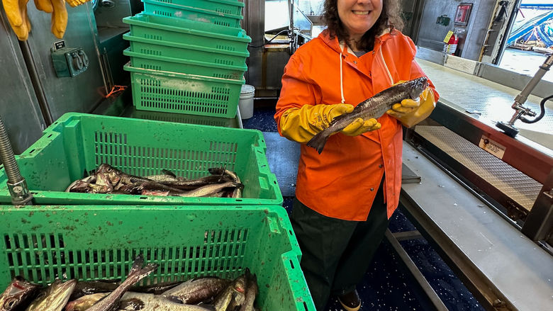 A woman on board a ship hold a fish.