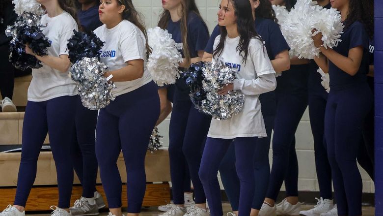 Members of the Hype Squad stand on the sideline during a basketball game.