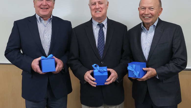 Three men hold boxes containing their gifts.