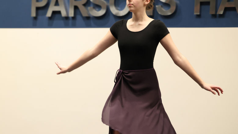 A female student is on a stage wearing a dance costume.