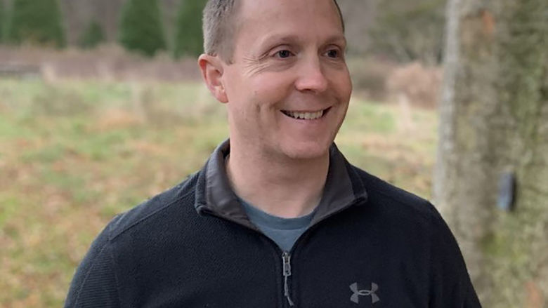 Daniel Hamilton stands outside with trees in the background