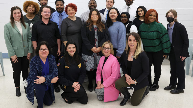 A group of people poses for a photo in front of a white wall.