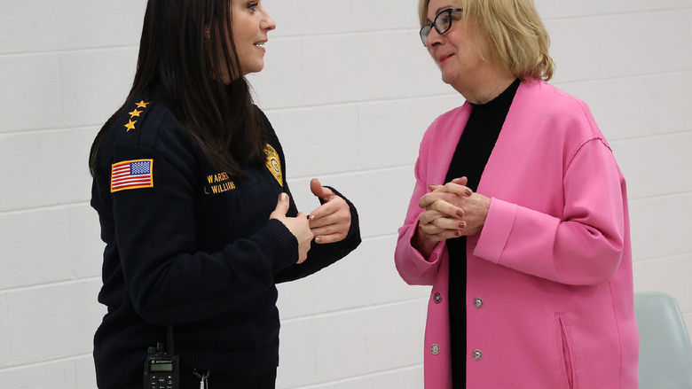 Two women stand talking to each other.